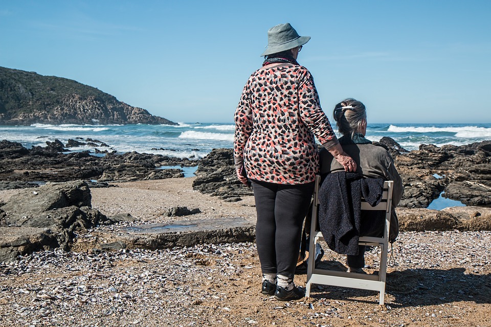 2 old ladies in the beach looking at the horizon