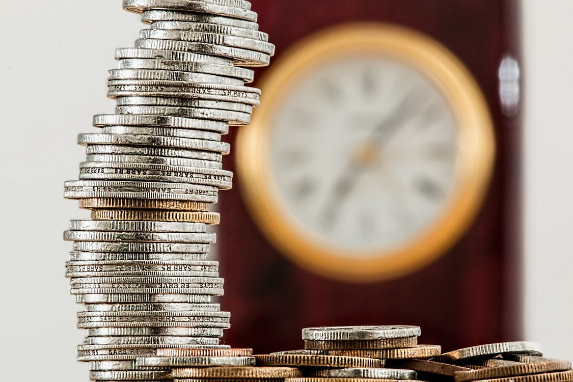 coins stacking and a clock blurred in the background