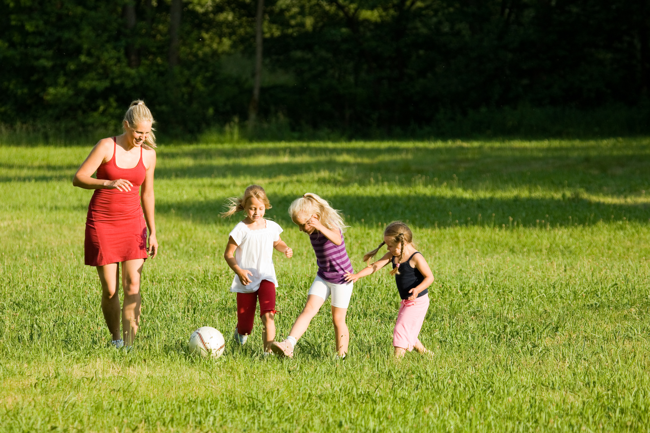 a mom and her three kids playing in the field